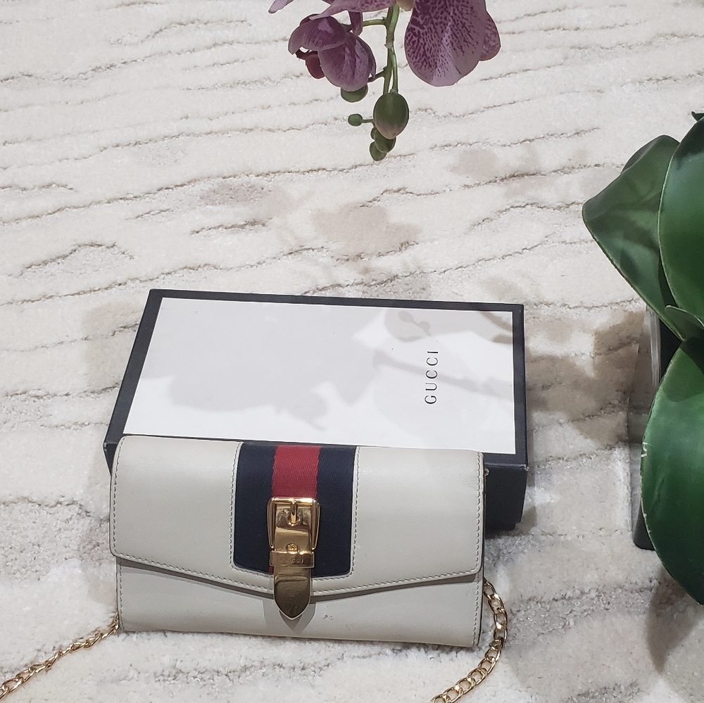 Off-white Gucci wallet on a chain with red, blue and gold accents.